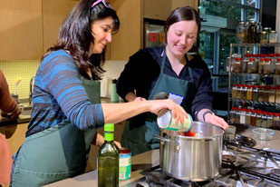 Two people puting vegetables into pot